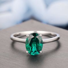 an oval cut emerald ring on a table