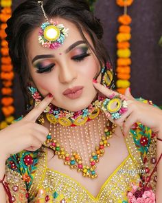 a woman with makeup and jewelry on her face, posing for a photo in front of flowers