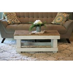 a living room with a couch, coffee table and rug on the floor in front of it