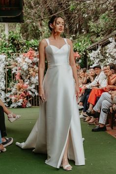 a woman in a white dress walking down the runway