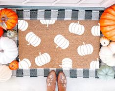 a person standing in front of a door mat with pumpkins on it