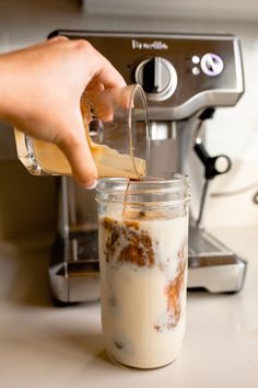 someone is pouring something into a glass in front of an espresso coffee maker