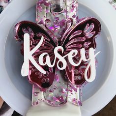 there is a plate with a butterfly on it and the word kasey spelled in white letters