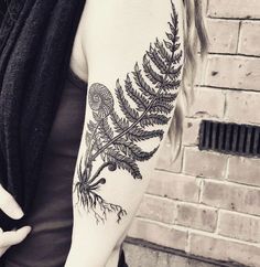 a black and white photo of a woman's arm with a fern tattoo on it