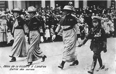 an old black and white photo of some women walking in front of a large crowd