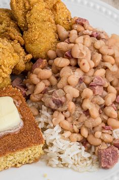 a white plate topped with rice, beans and cornbreads next to fried chicken