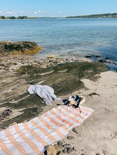 an orange and white striped towel laying on top of a beach next to the ocean