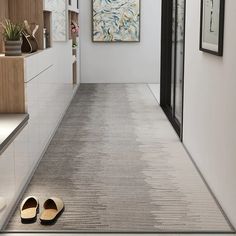 a pair of slippers sitting on the floor in a hallway next to a painting