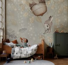 a child is sitting on a bed with an animal wallpaper