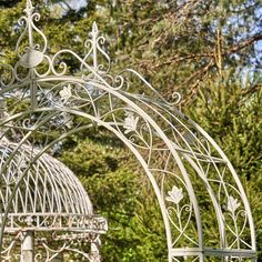 an iron gazebo in the middle of some trees