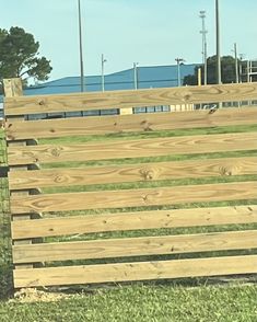 an animal that is standing in the grass next to a fence and some poles with lights on them