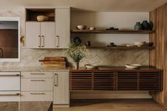 a kitchen with white cabinets and marble counter tops, wooden shelves and open shelving