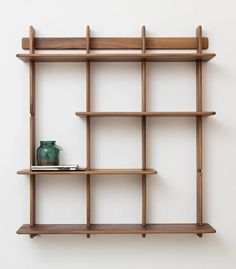 a wooden shelf with two vases on top of it next to a white wall