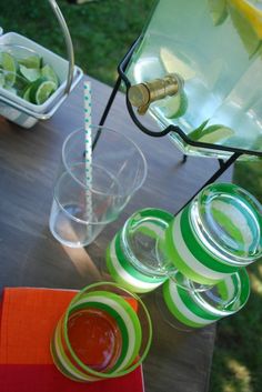 a table topped with glasses filled with liquid and limes on top of each other