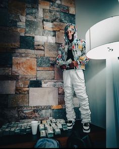 a man standing in front of a stone wall with stacks of money on the floor