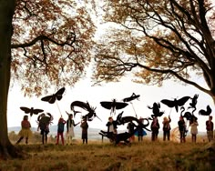 a group of people standing next to each other in front of trees with birds on their heads