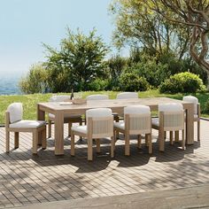 a wooden table with white chairs around it on a brick patio next to some trees