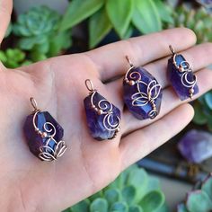 three pieces of jewelry sitting on someone's hand next to some succulent plants