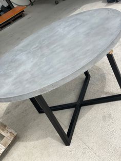 an oval concrete table sitting on top of a metal stand in a room with other items