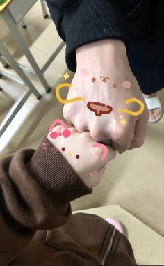 two people holding hands with faces drawn on them