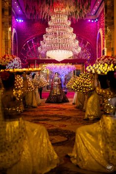 the bride and groom are standing in front of an elaborate chandelier