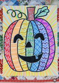 an art project made with colored papers and paper machs, including a pumpkin face