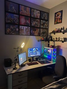 a computer desk with two monitors and a keyboard on it in front of a wall full of pictures