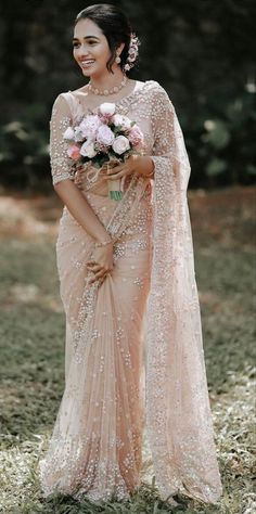 a woman in a pink sari with flowers on her head and holding a bouquet