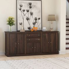 an art piece on top of a wooden sideboard in a living room with stairs leading up to the second floor