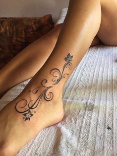 a woman laying on top of a bed with a tattoo on her leg and foot