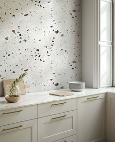 a kitchen counter with a vase on top of it next to a window and white cabinets