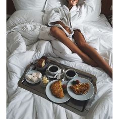 a person laying in bed with food on a tray