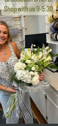 a woman holding a bouquet of flowers in front of a store sign that says congratulations here shop with us 9 - 3 30