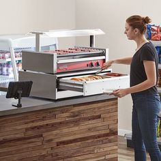 a woman standing in front of a counter with donuts on it and an oven