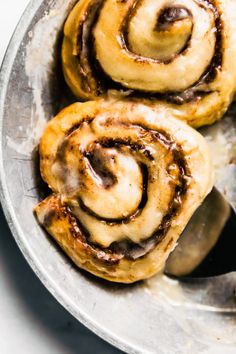 three cinnamon rolls sitting on top of a metal pan