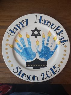 a happy hanukkah plate with handprints on it and the name simon 2013