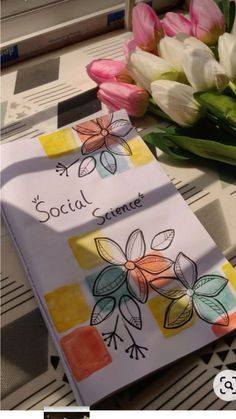 some flowers are sitting on a table next to two cards with the words social science written on them