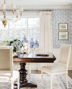 the dining room table is set with blue and white flowers on the wall behind it