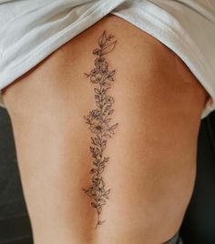 a woman's lower back tattoo with flowers on her left side ribcage