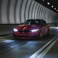 a red car driving through a tunnel with lights on it's headlamps