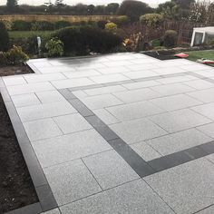 an outdoor patio with grey tiles and grass