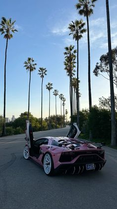 a pink sports car parked in front of palm trees