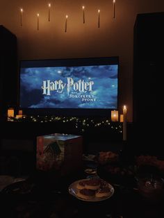 a harry potter movie is projected on the wall behind a table with cupcakes