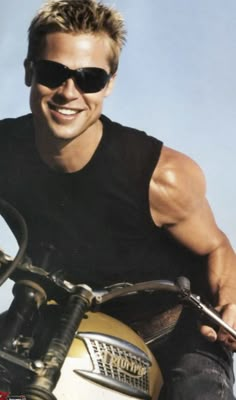 a man riding on the back of a motorcycle wearing sunglasses and smiling at the camera