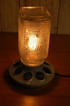 a glass jar sitting on top of a wooden table next to a plugged light