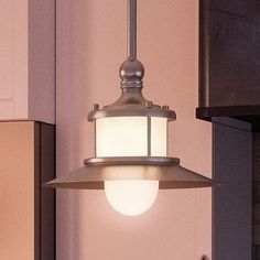 a light fixture hanging from the side of a kitchen wall next to a stove top oven