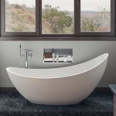 a large white bathtub sitting in front of a window next to a counter top