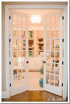 an open door leading to a living room with white walls and wood flooring in front of it