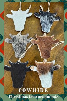 cowhide christmas tree ornaments are hanging on a wooden table with an ornament in the middle