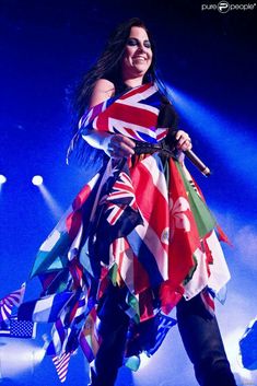 a woman in a colorful dress on stage with flags all over her body and legs